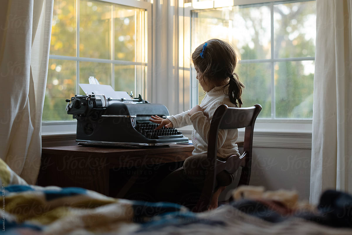 Little girl typing on typewriter keyboard