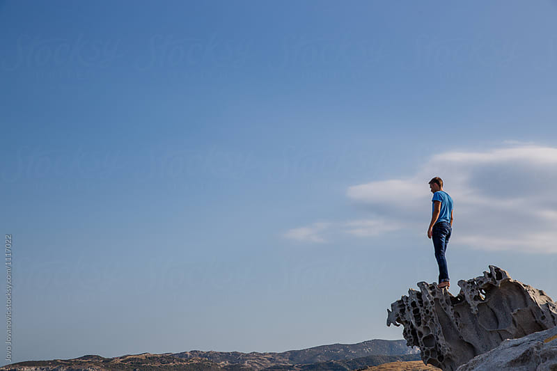 Man standing on a rock by the sea and watching the horizon