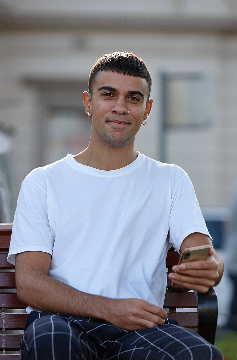 Young Indigenous Australian man smiling using mobile phone outdoors