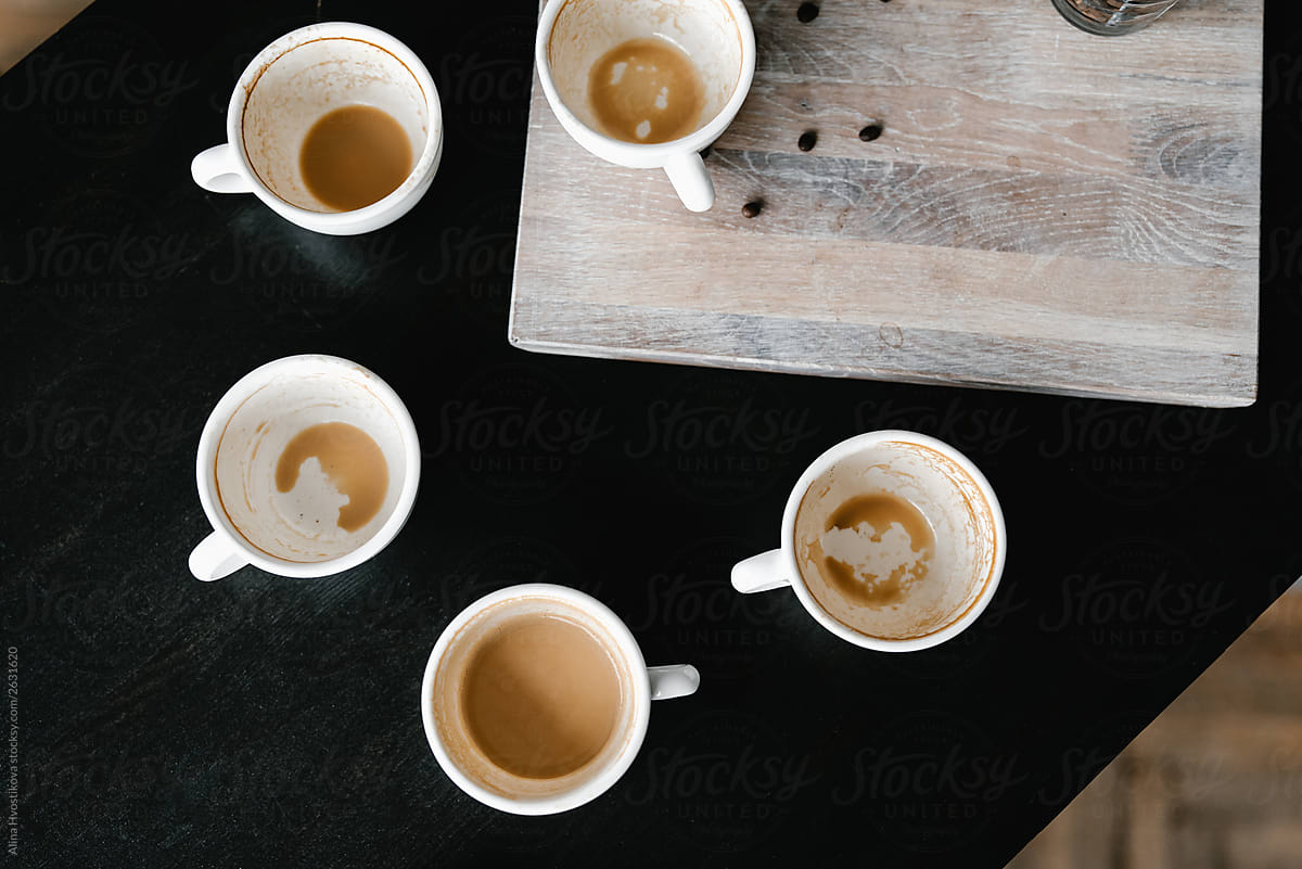 Above view of five dirty cups on black table.