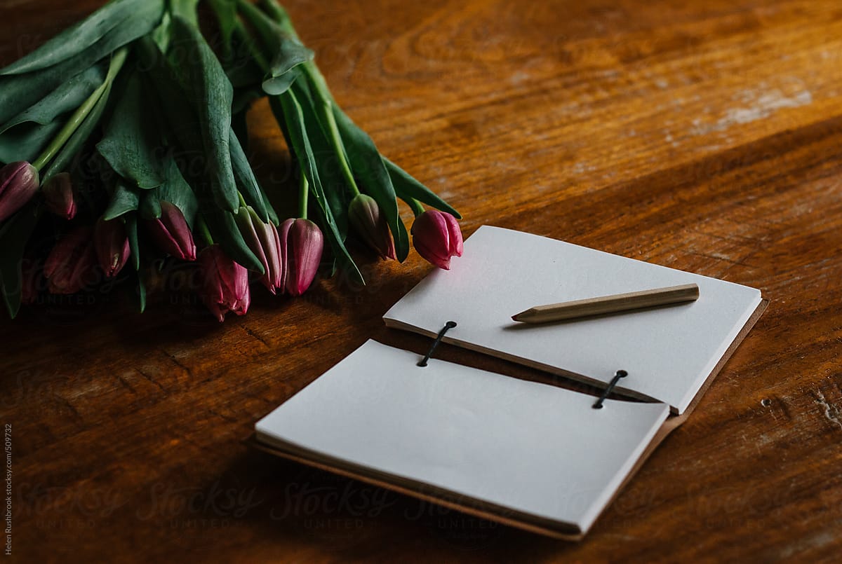 Pink tulips and a blank journal on a table