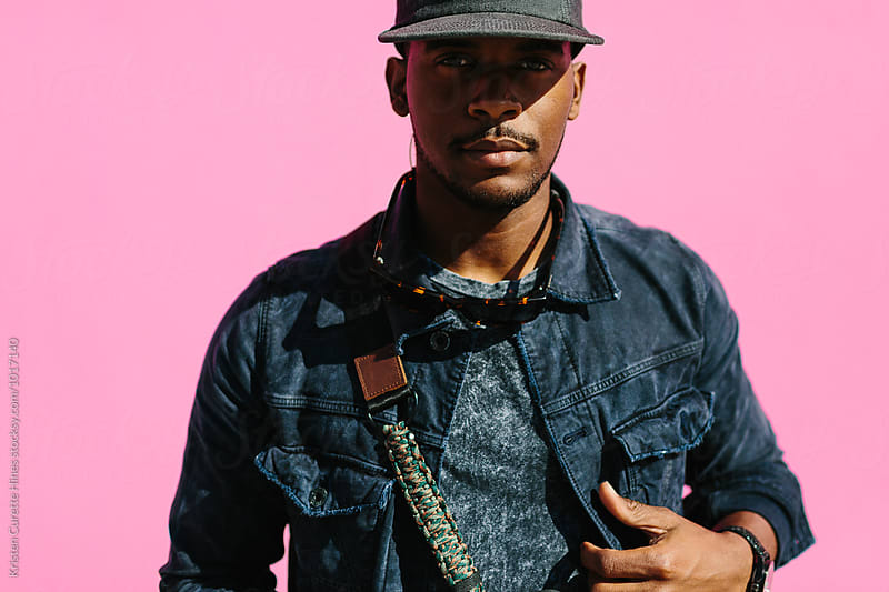 Portrait of an African American man against a pink wall.