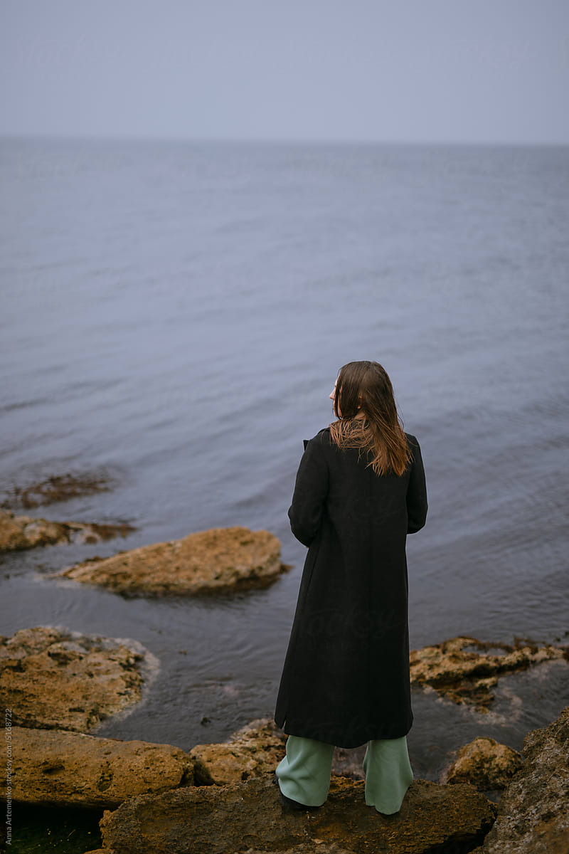 woman in black coat by the sea
