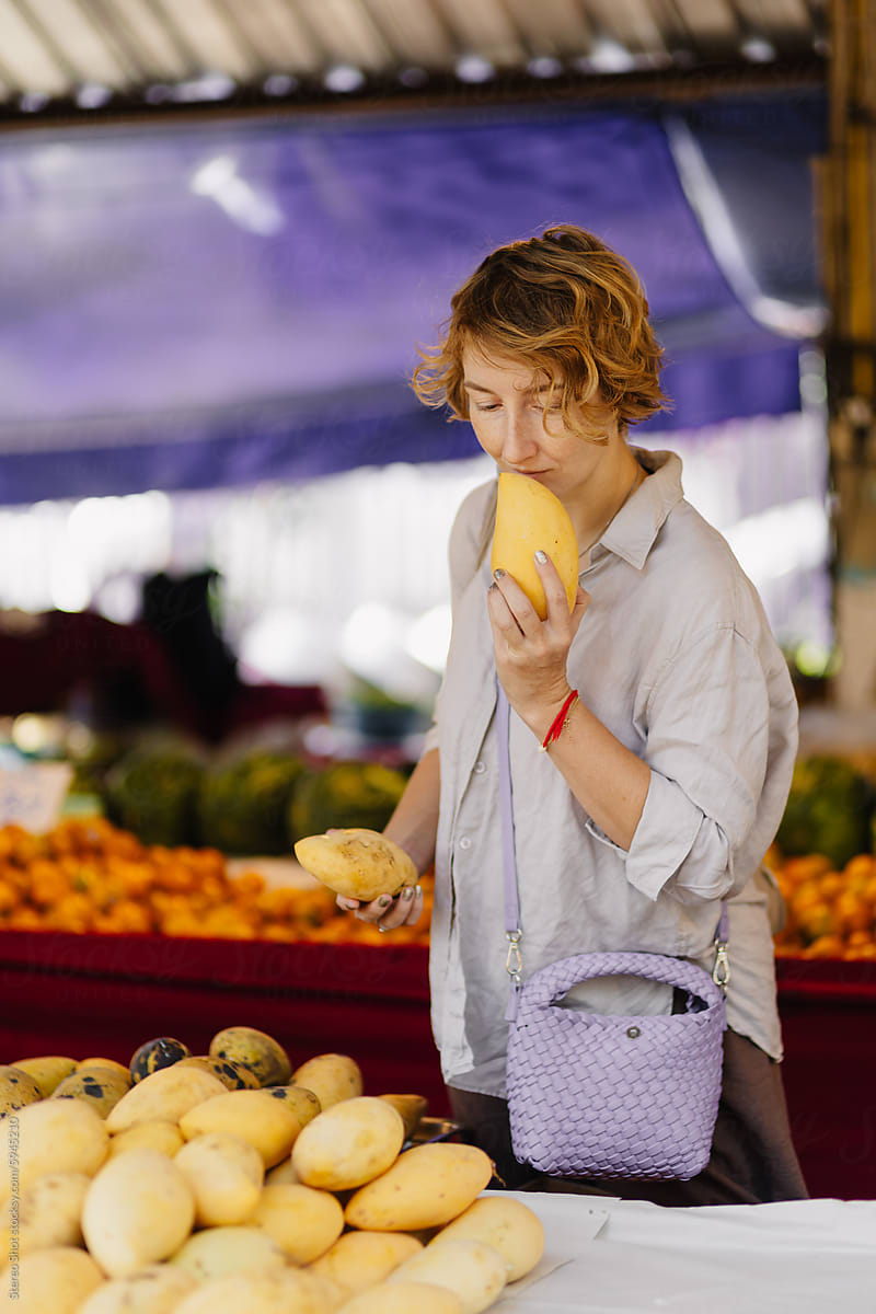 Woman smelling mango fruit in authentic market