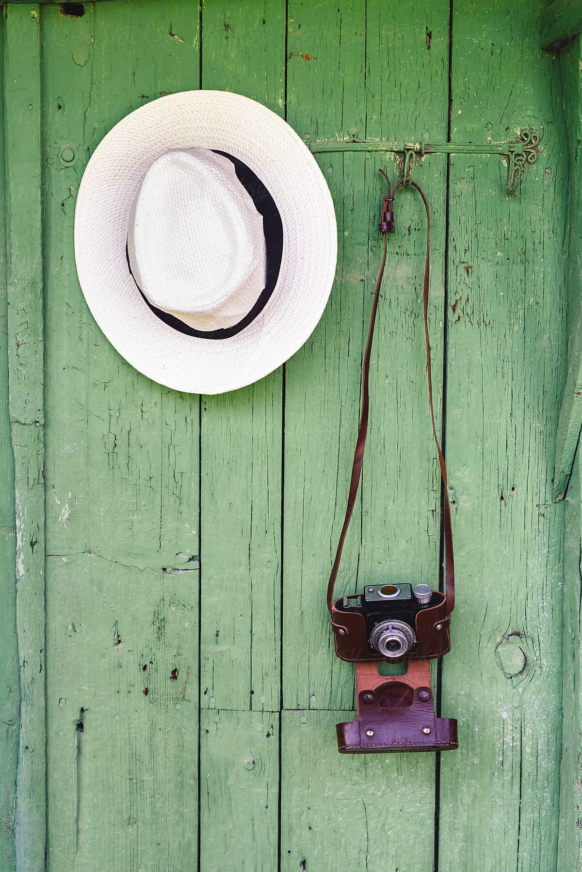 Vintage film camera and hat on green wall hanger