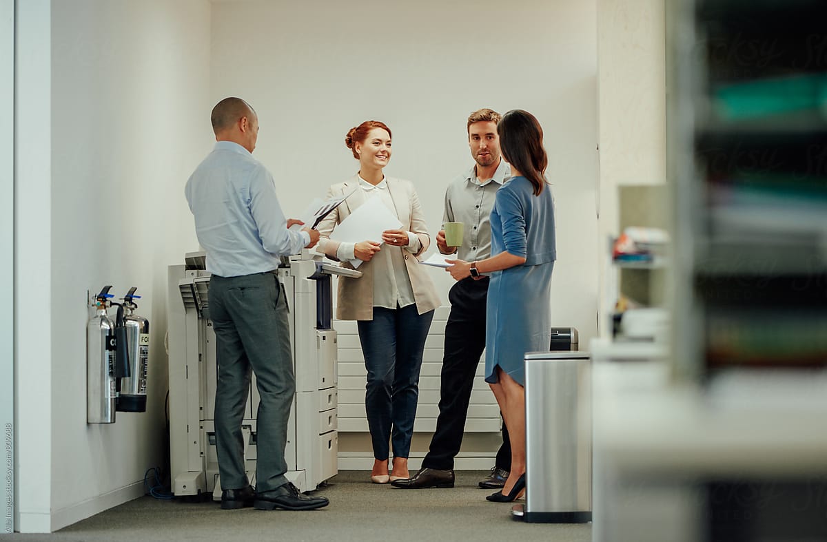 Young diverse business people interacting next to office photocopier