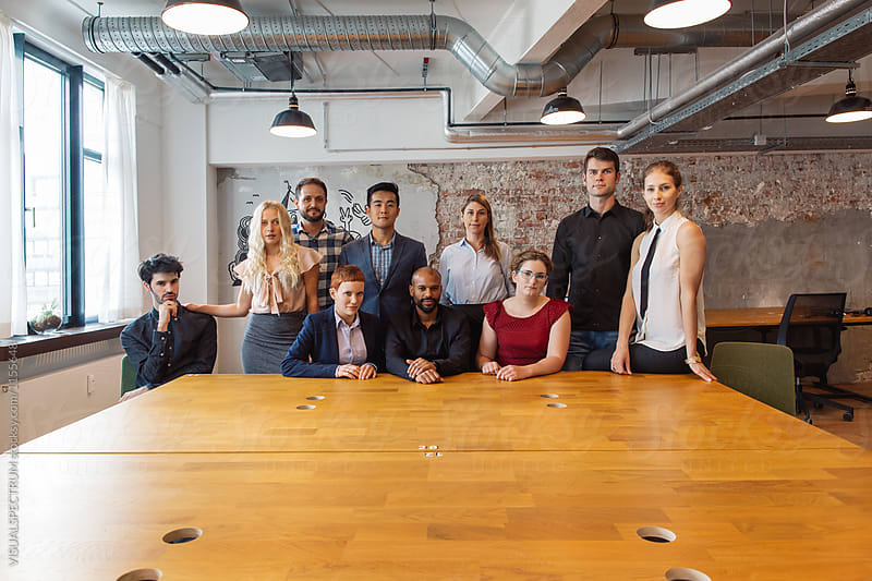 Indoor Group Shot of Young Employees Standing Around Large Table