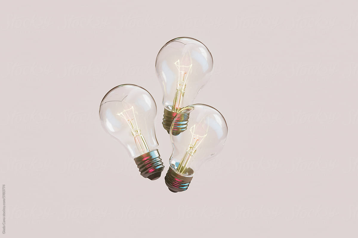 Trio of Glowing Light Bulbs on Pastel Pink Background