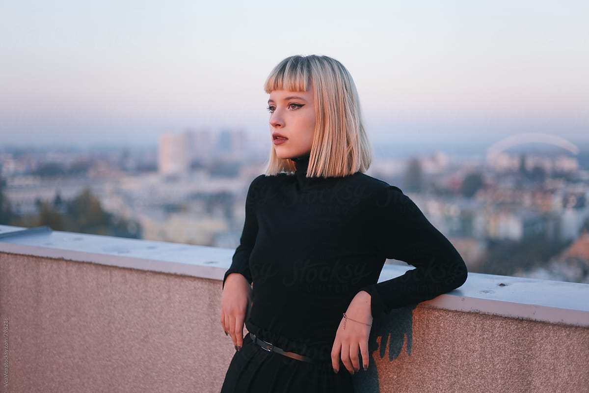 Portrait of a beautiful young woman on the roof of the building during sunset