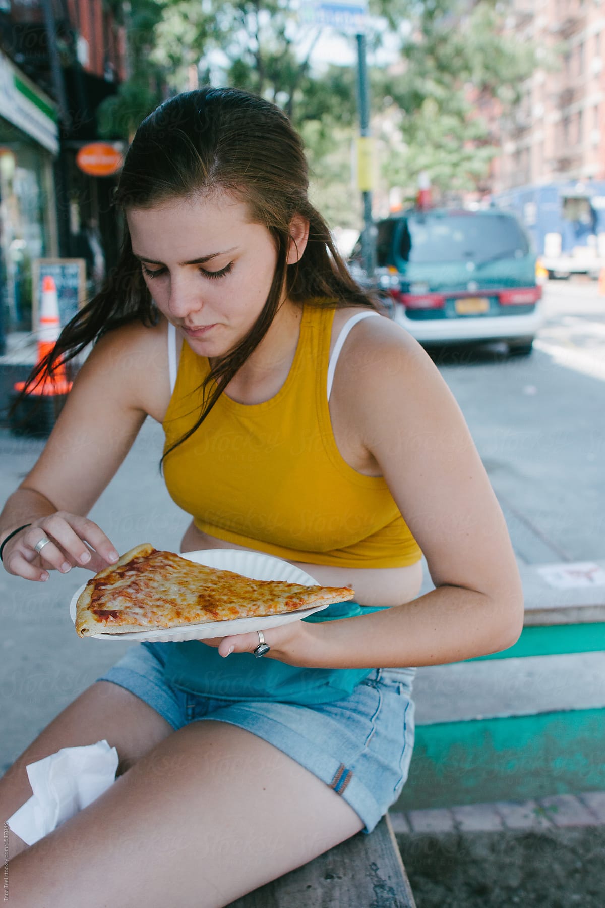 teenager eating a slice of New York pizza on summer day