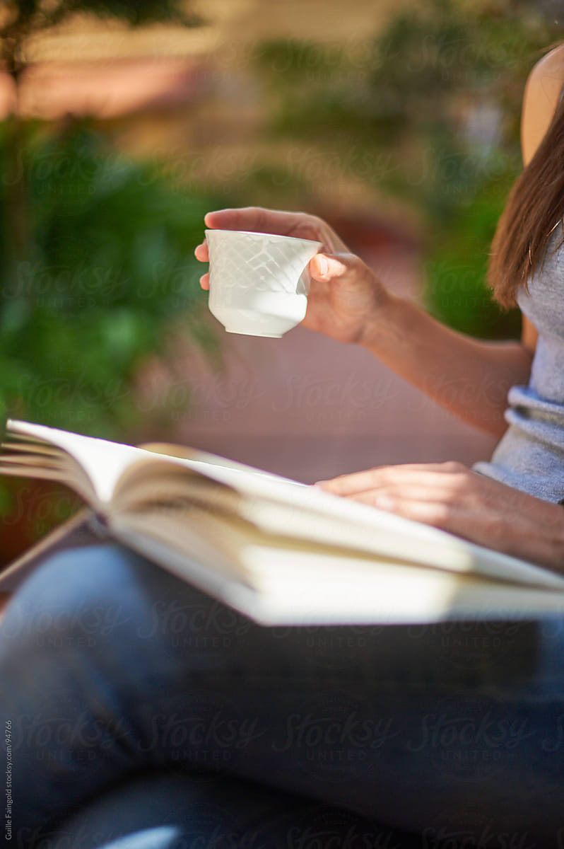 Reader with book and cup outside