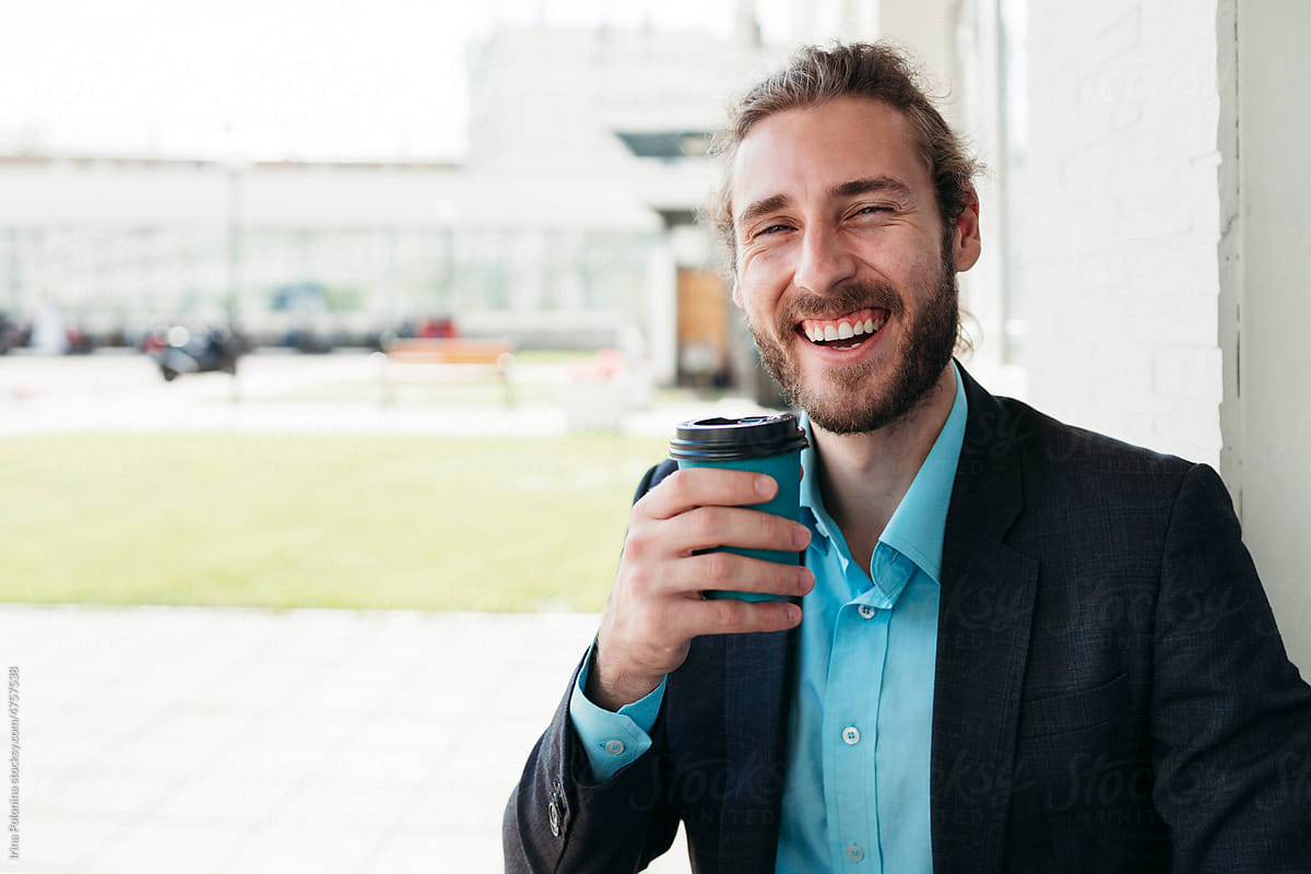 Happy man holds in hands disposable cup with coffee.