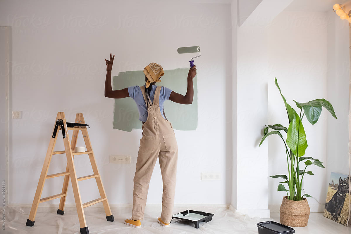 Black painter gesturing V sign near ladder