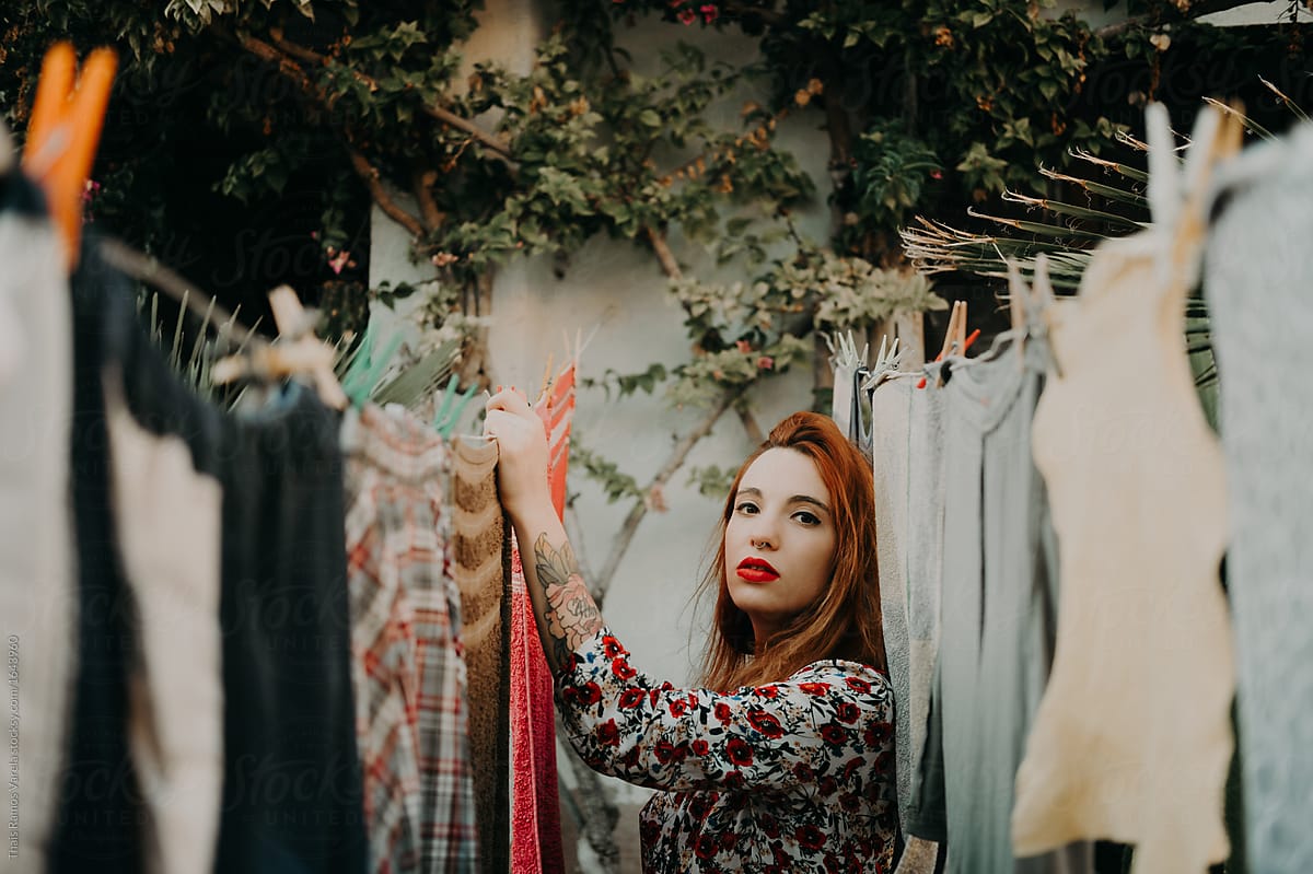 Portrait Of A Beautiful Ginger Woman Between Hanging Clothes By Stocksy Contributor Thais