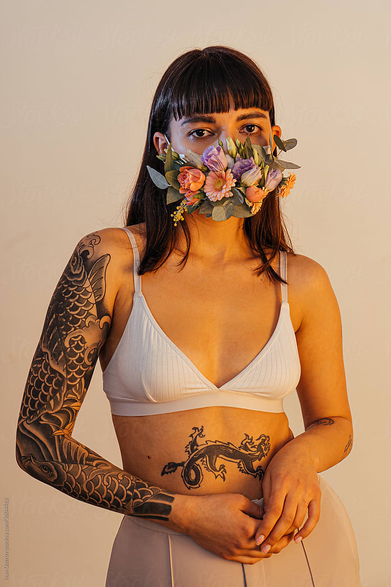 gentle woman in bra and flower mask in studio