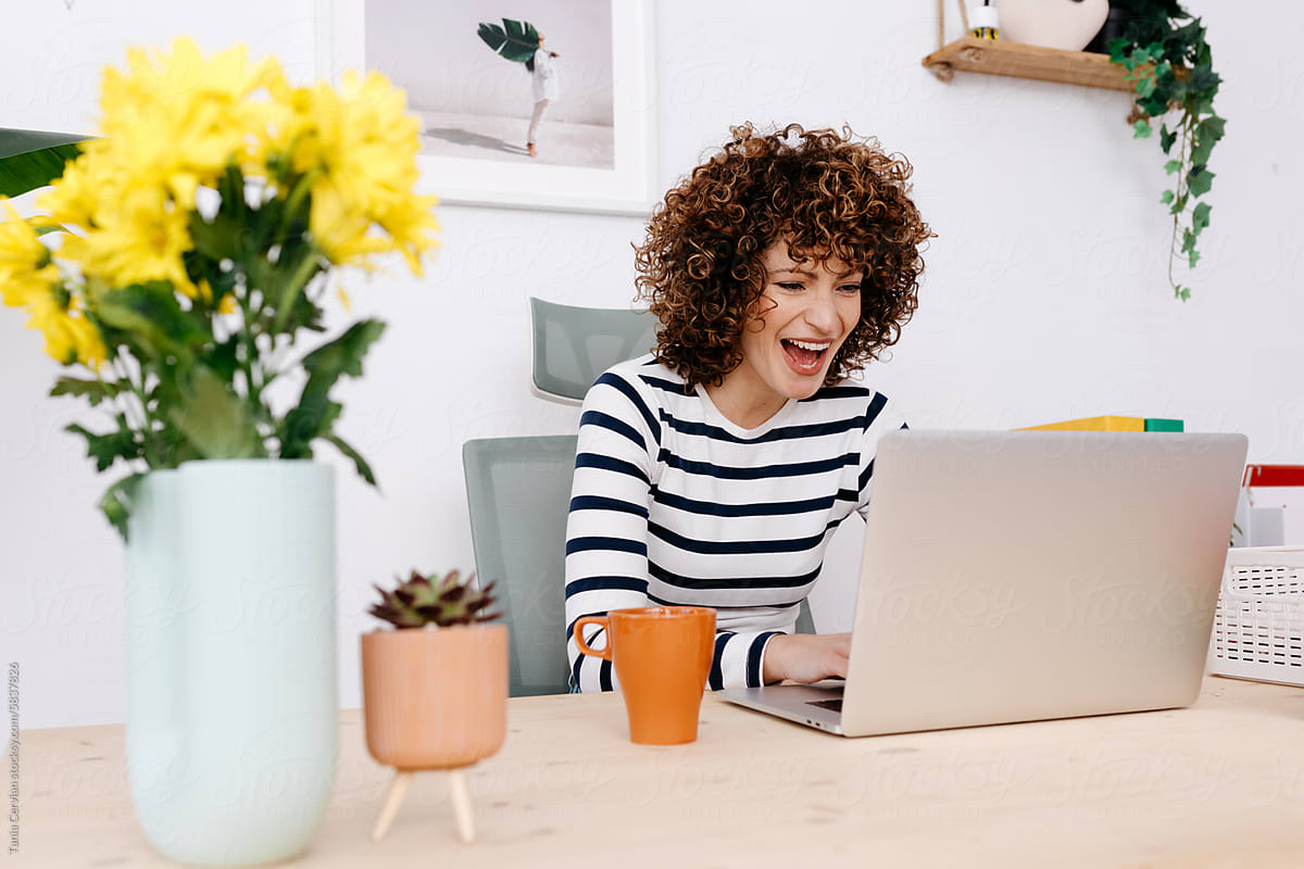 Woman laughing and browsing internet with laptop
