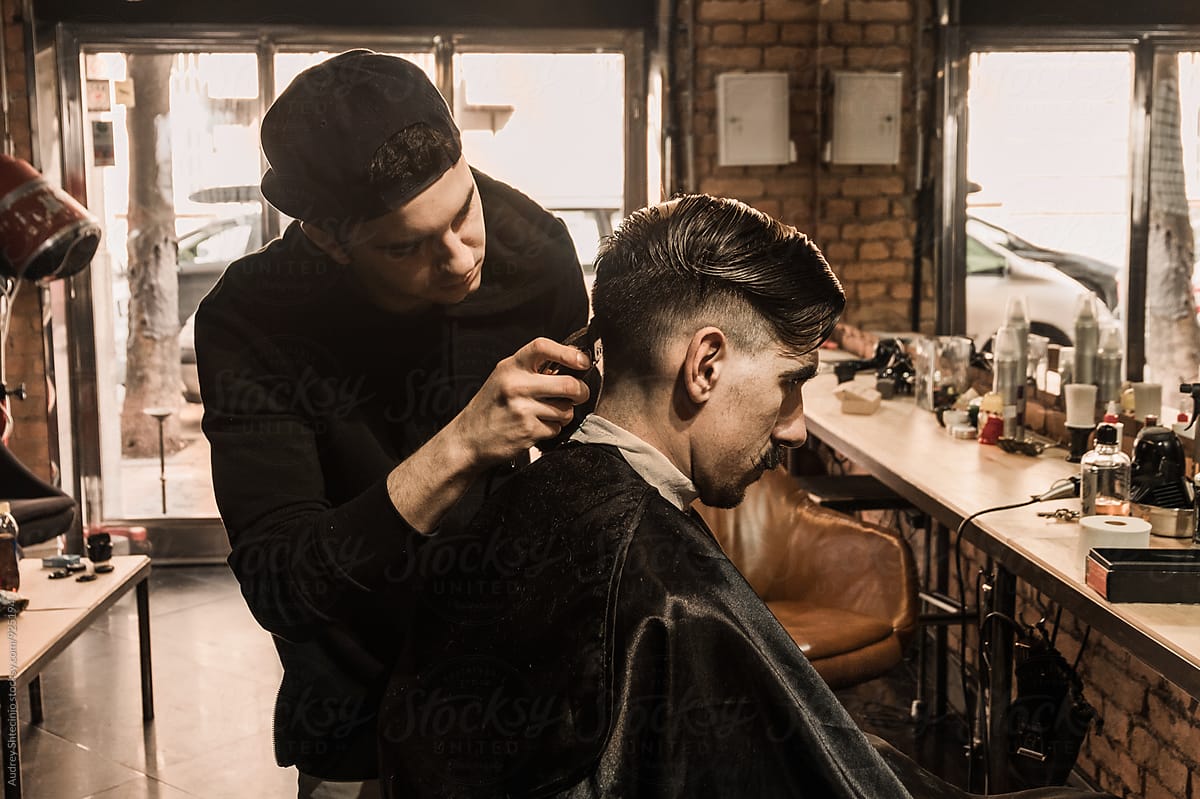 YOung barber working in vintage barber shop.