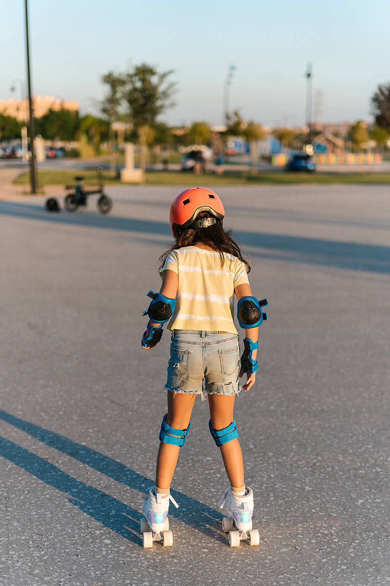 Girl in protective helmet roller skating on street