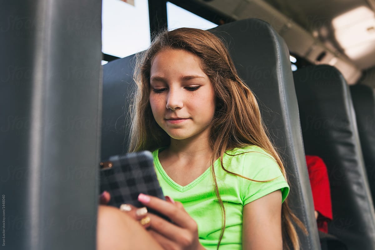 School Bus: Girl Riding Bus Checks Cell Phone