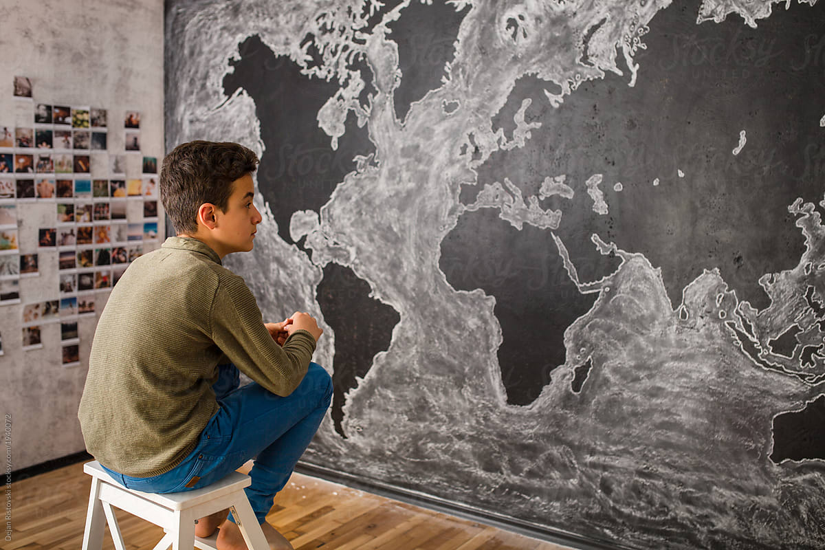 Boy drawing world\'s map in the classroom
