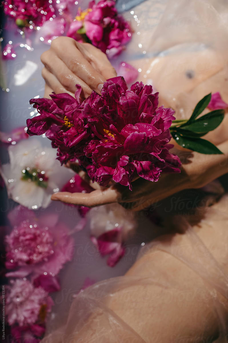 faceless woman in bath holding wet and beautiful flowers