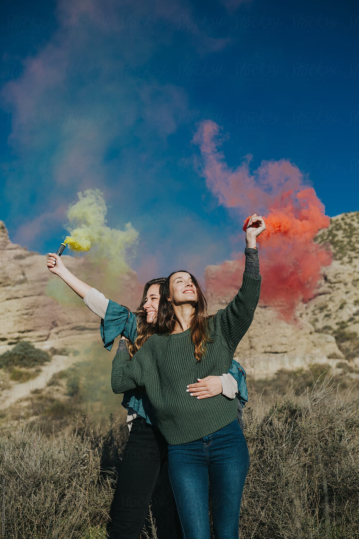 Cheerful teenagers playing with color smoke bombs in the country
