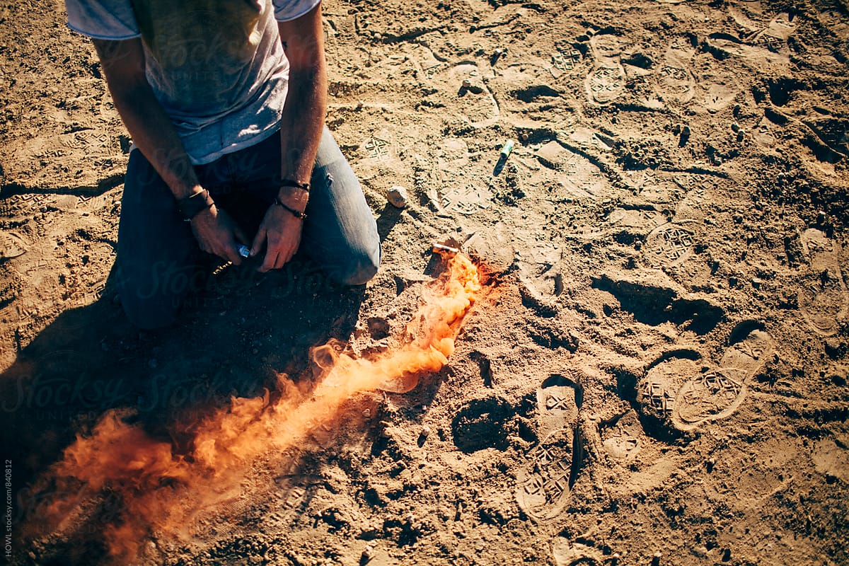A man kneeling in the dirt next to a trail of fire