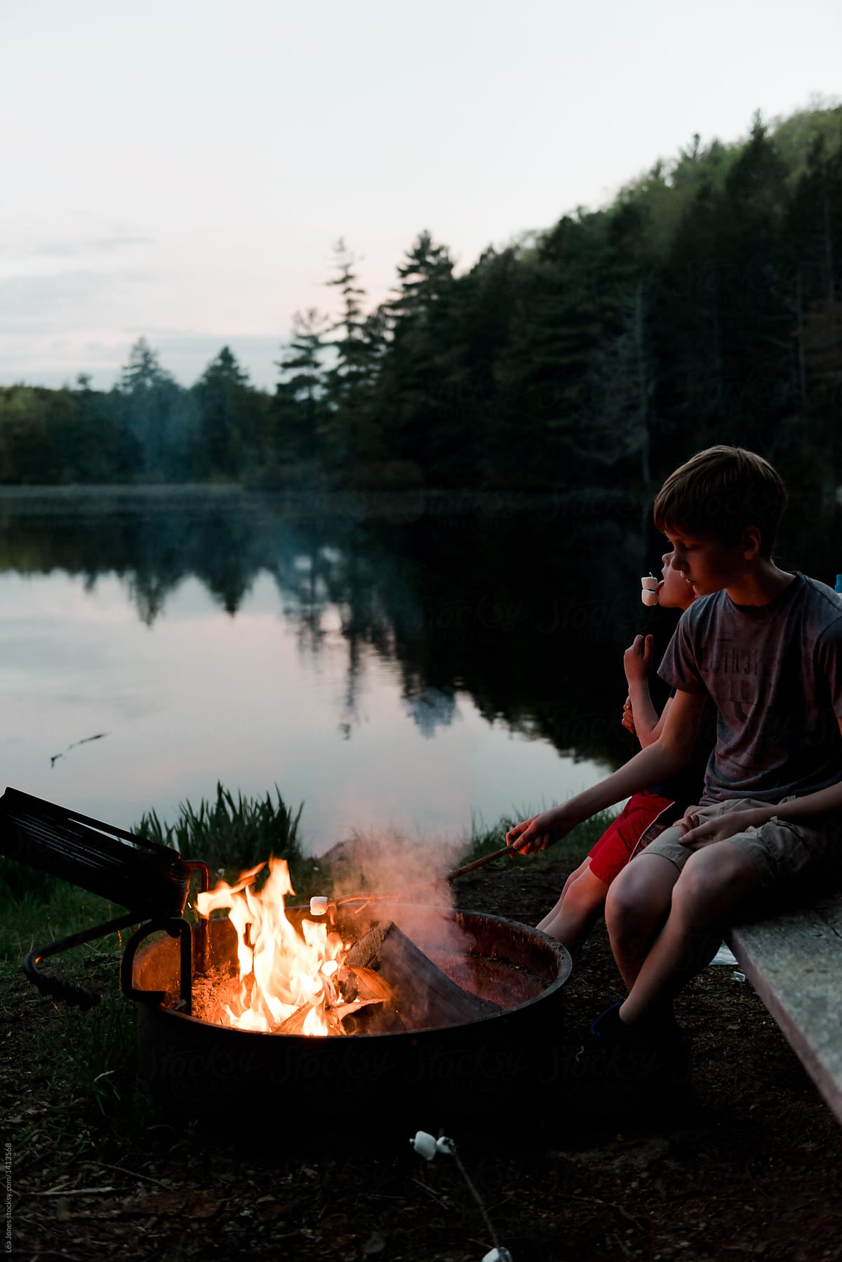 teenage boy grilling marshmallows on campfire