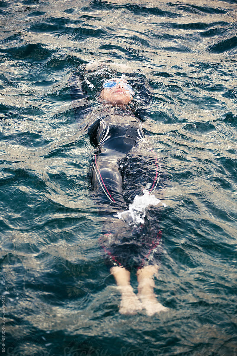 Woman wearing a wetsuit floating in water.