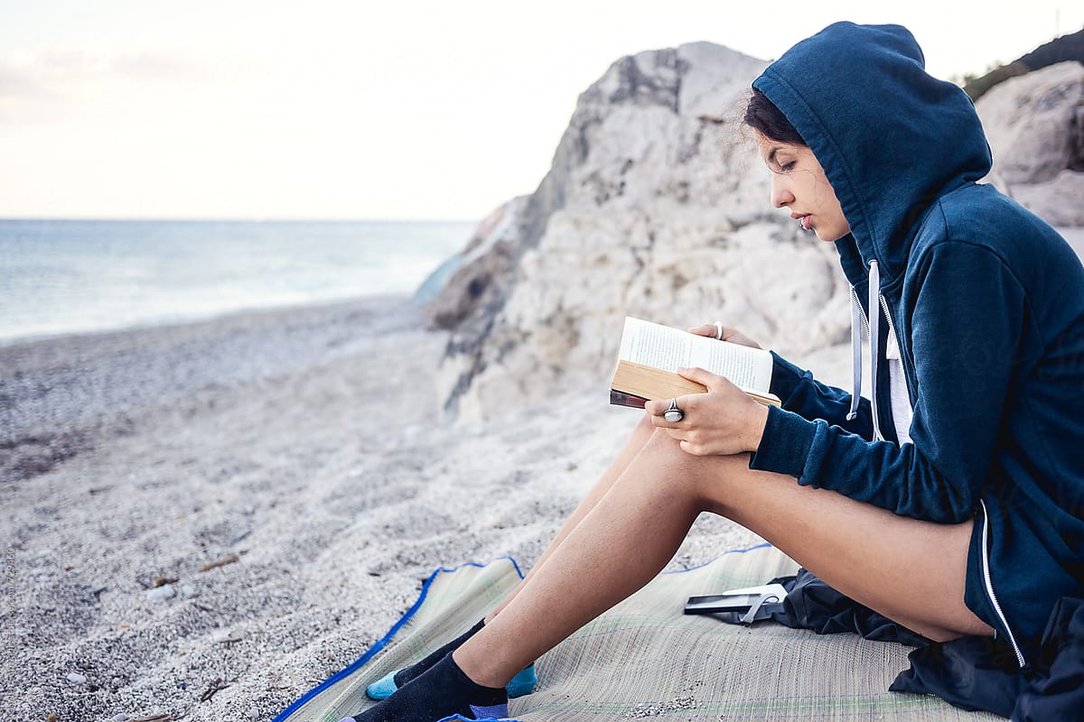 Young Woman Reading a Book on the Beach