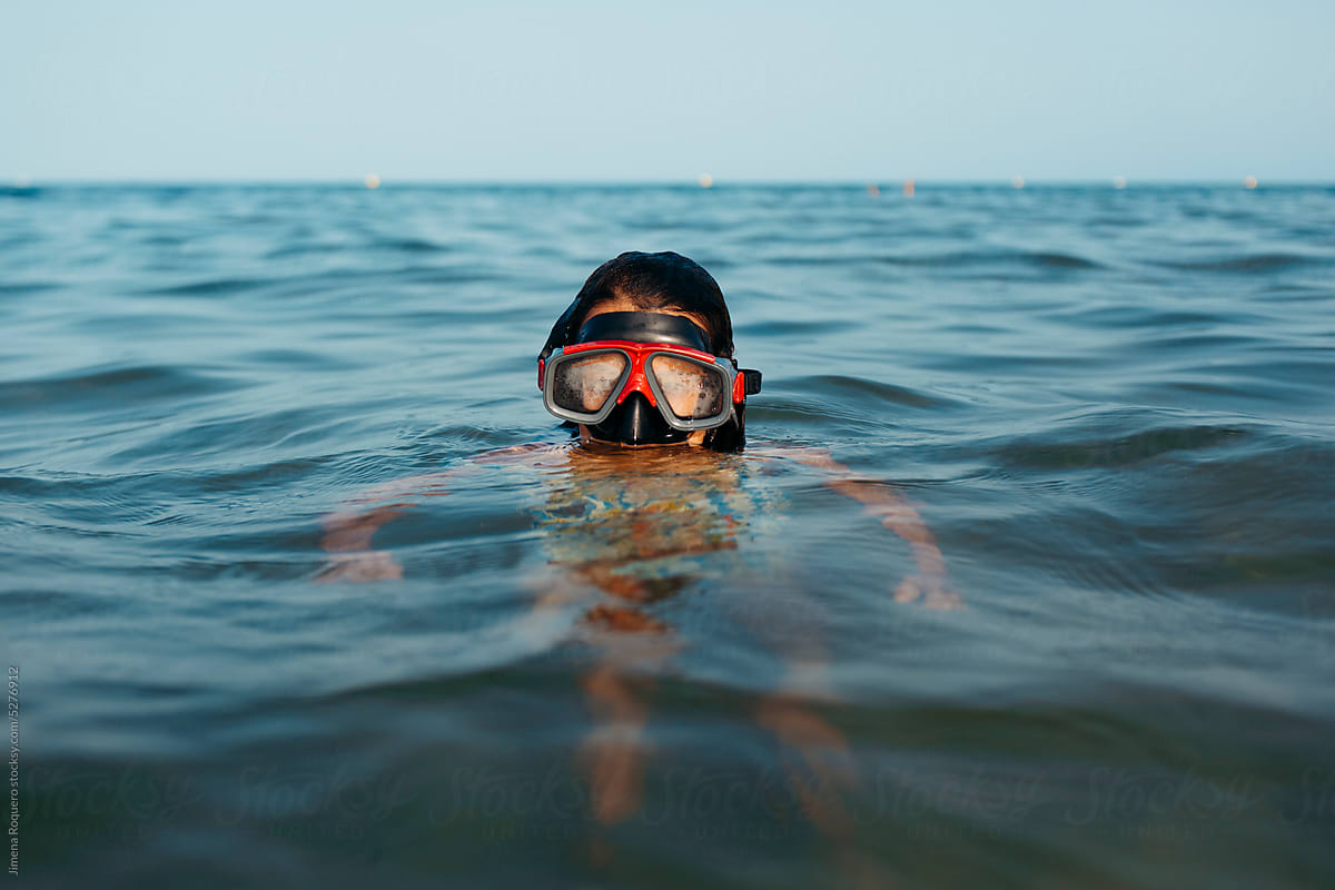 Child with diving goggles inside seawater