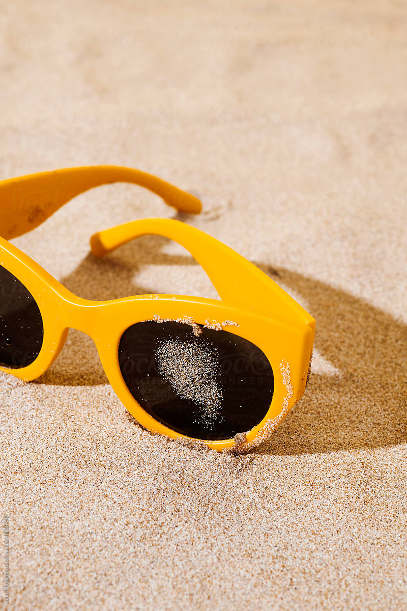 yellow plastic-rimmed sunglasses on the sand