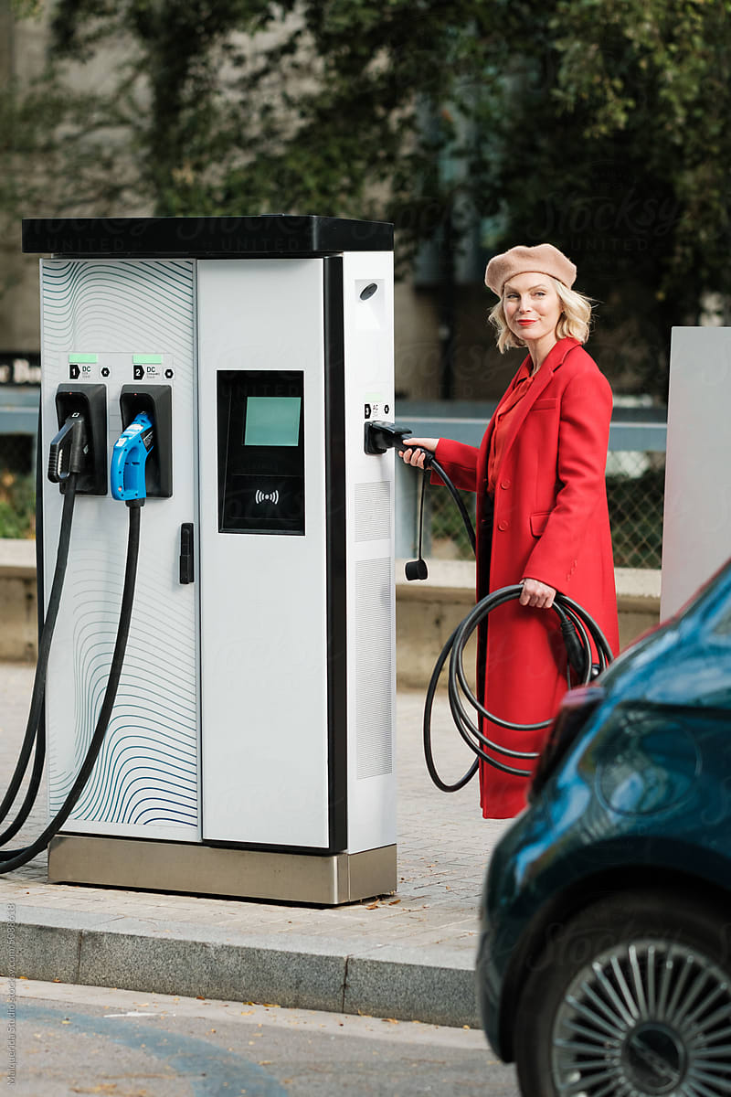 Woman plugs in Electric Car on Charge Station
