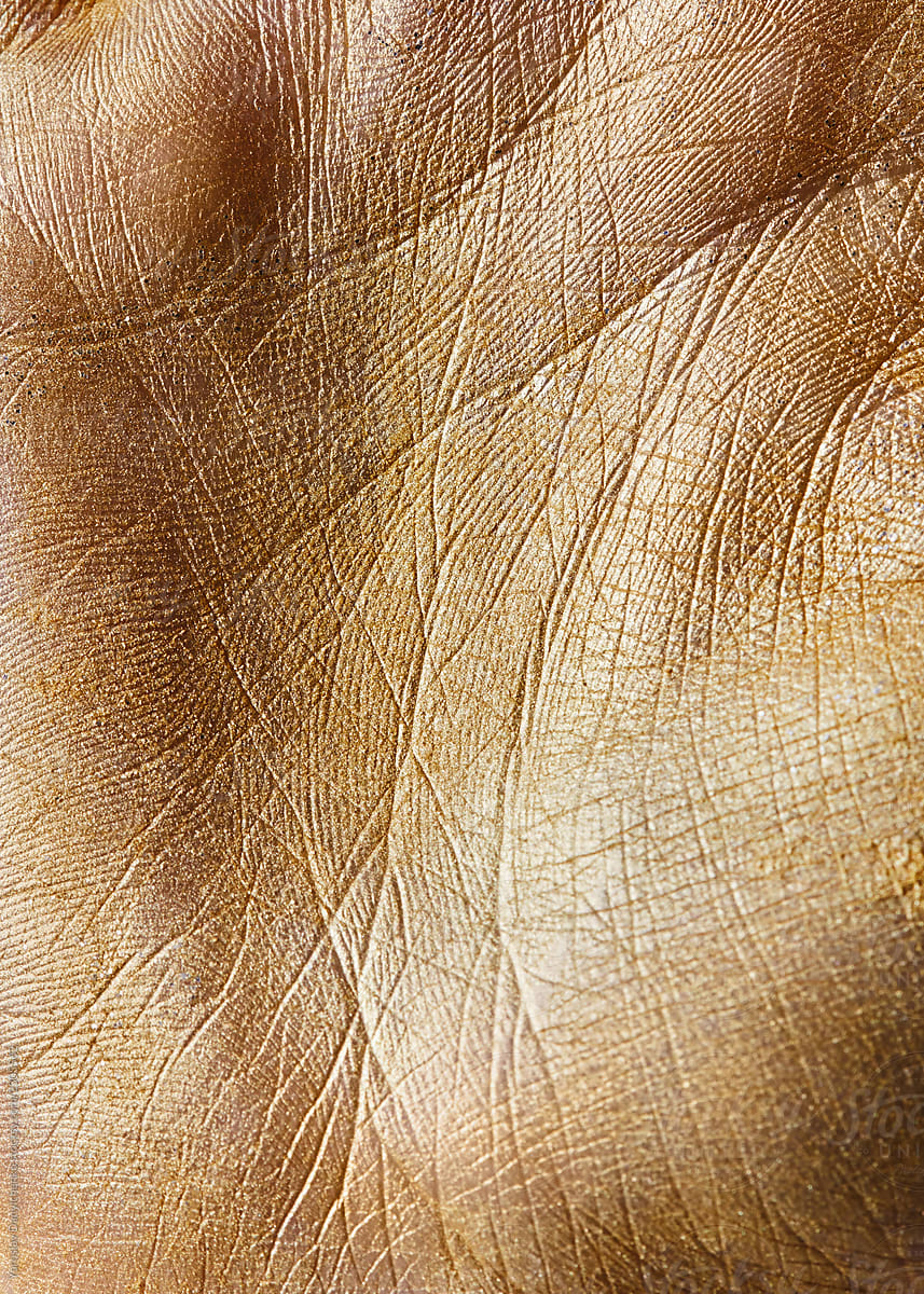 Macro photo of a handbreadth painted gold powder with a pattern of lines