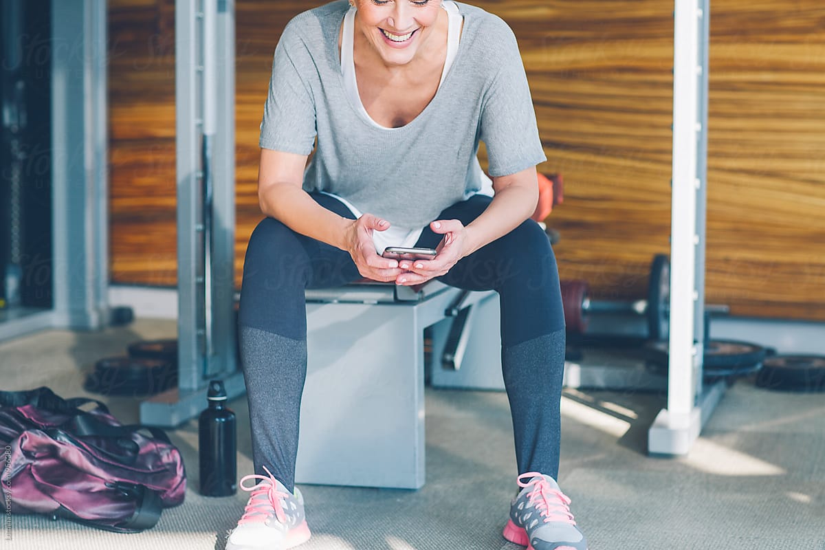 Woman Using A Mobile Phone In The Gym Del Colaborador De Stocksy Lumina Stocksy