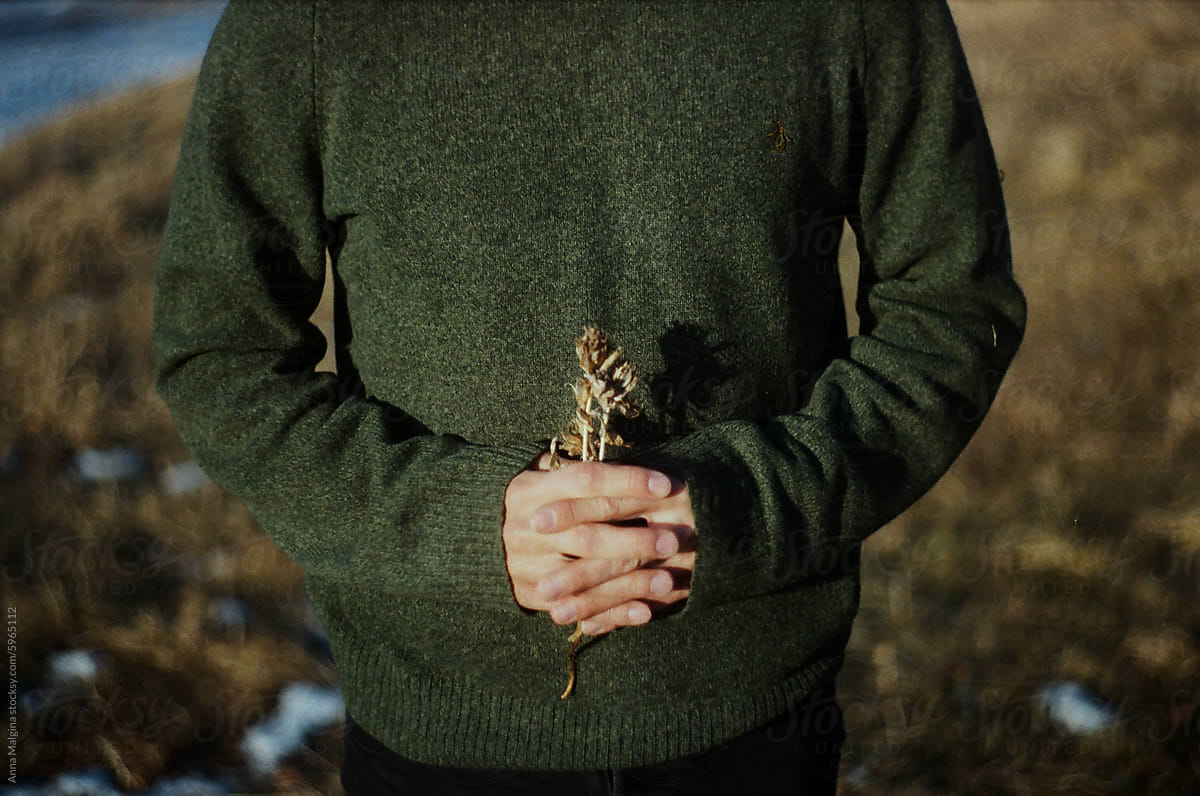Man Holding Dried Plant Against Green Sweater