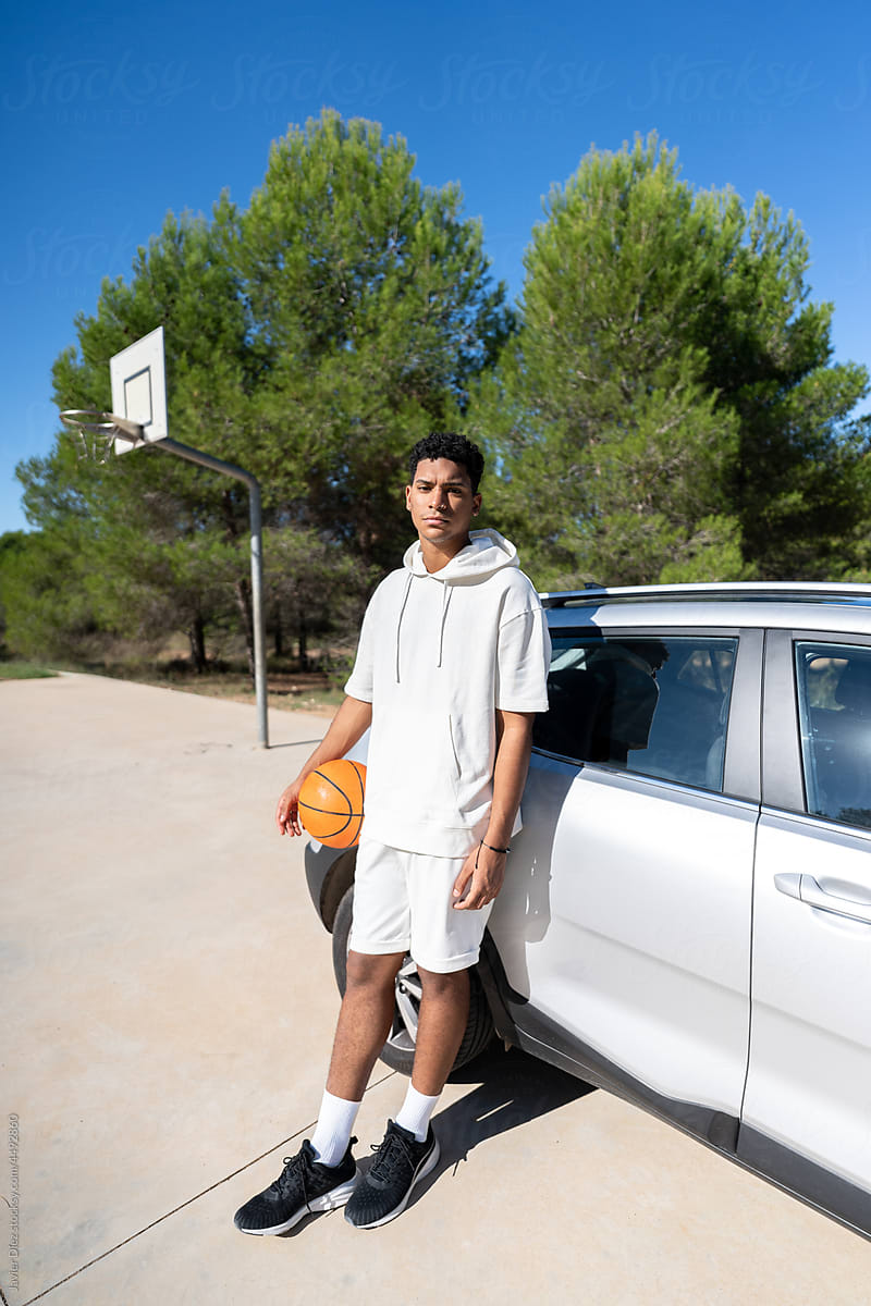 Basketball player leaning on car