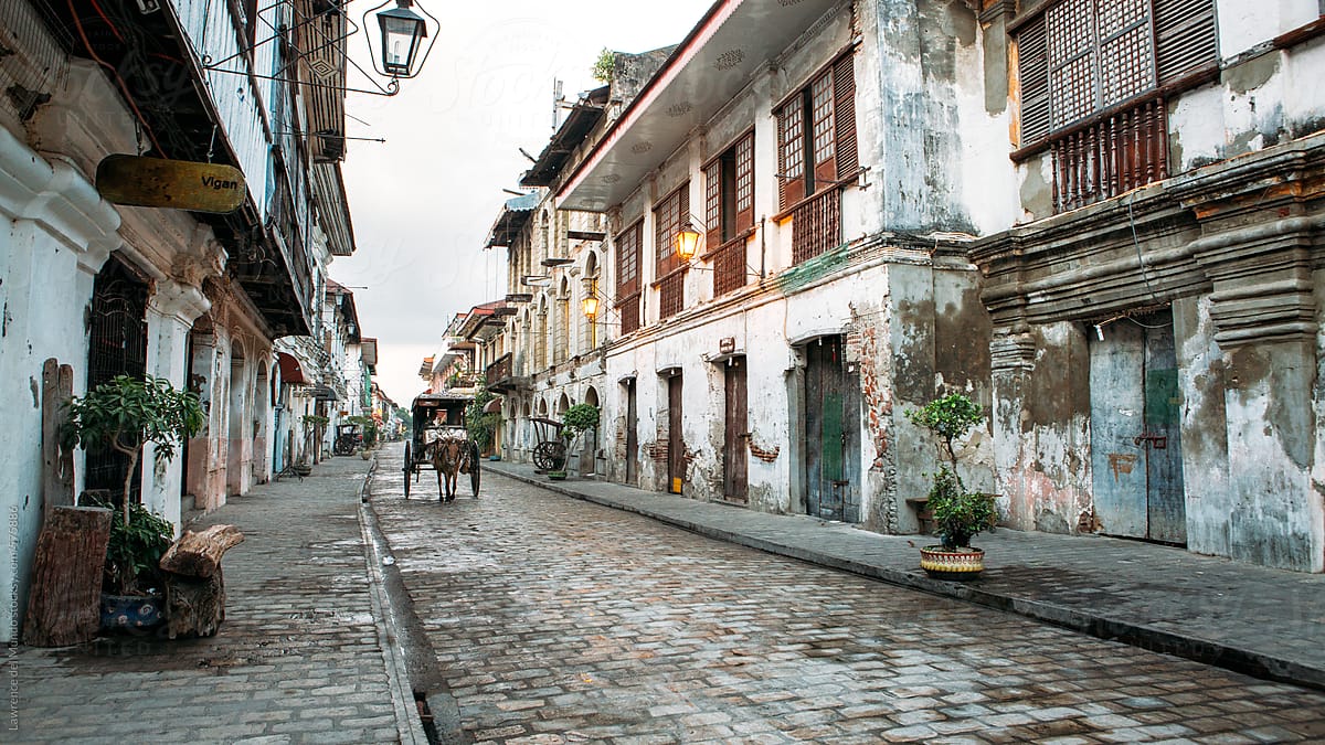 A horse-drawn carriage moves along an empty street of a historic town.