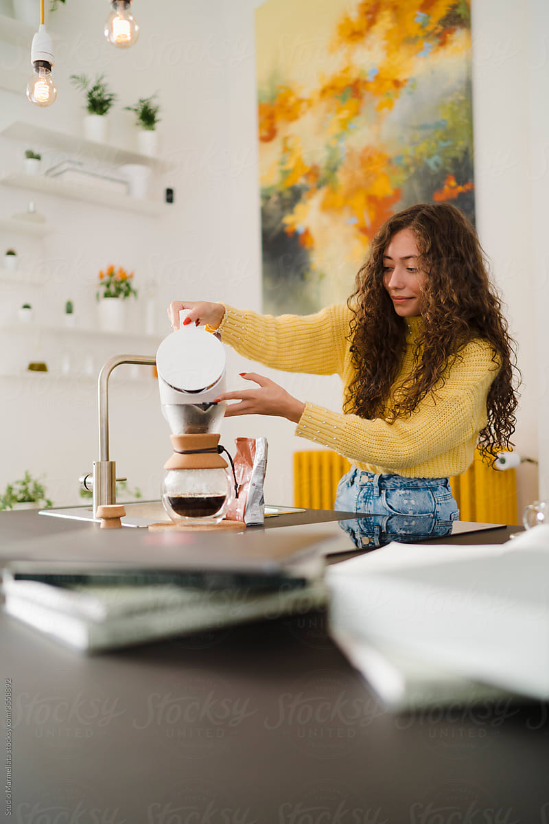 Young woman brewing pour over coffee