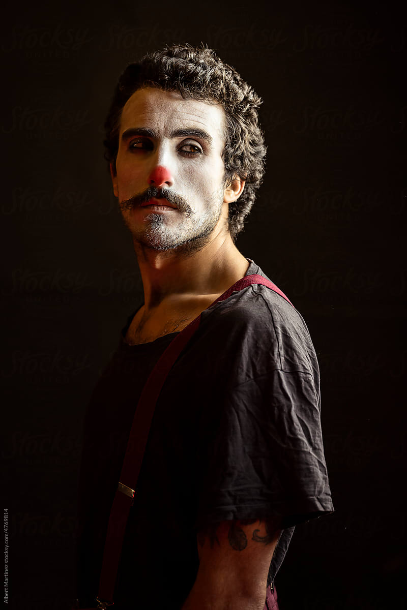 Serious male clown with makeup gazing at camera