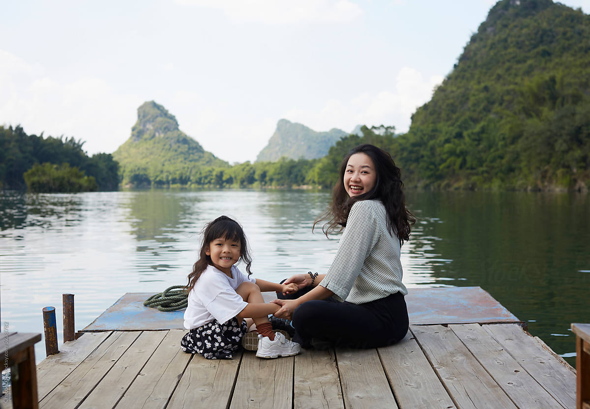 Asian mother and daughter playing on the edge of the Li River