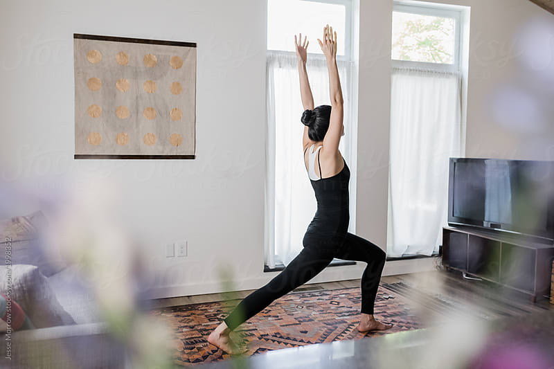 woman practices yoga in modern home living room