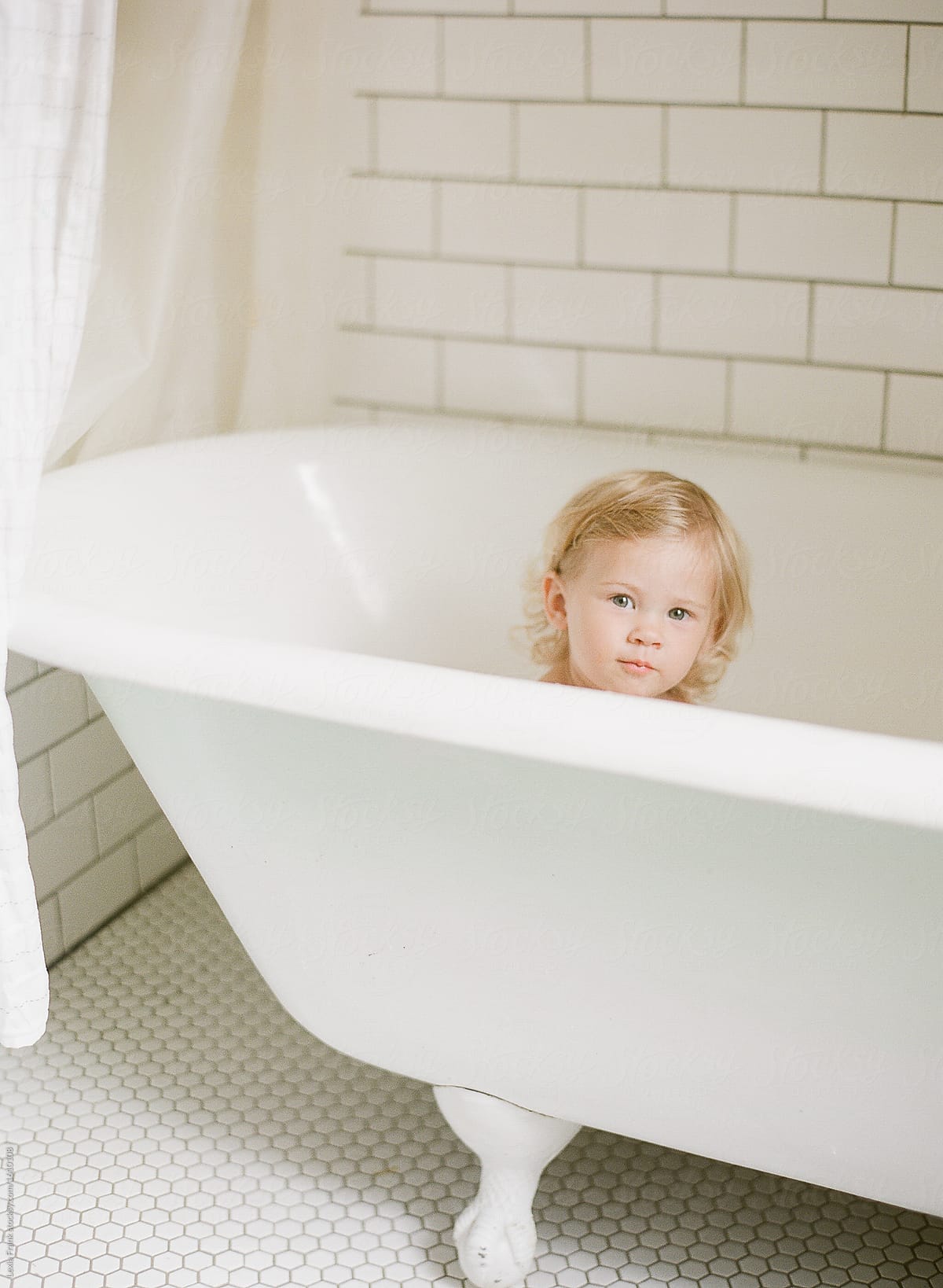 baby in bubble bath in white bathroom