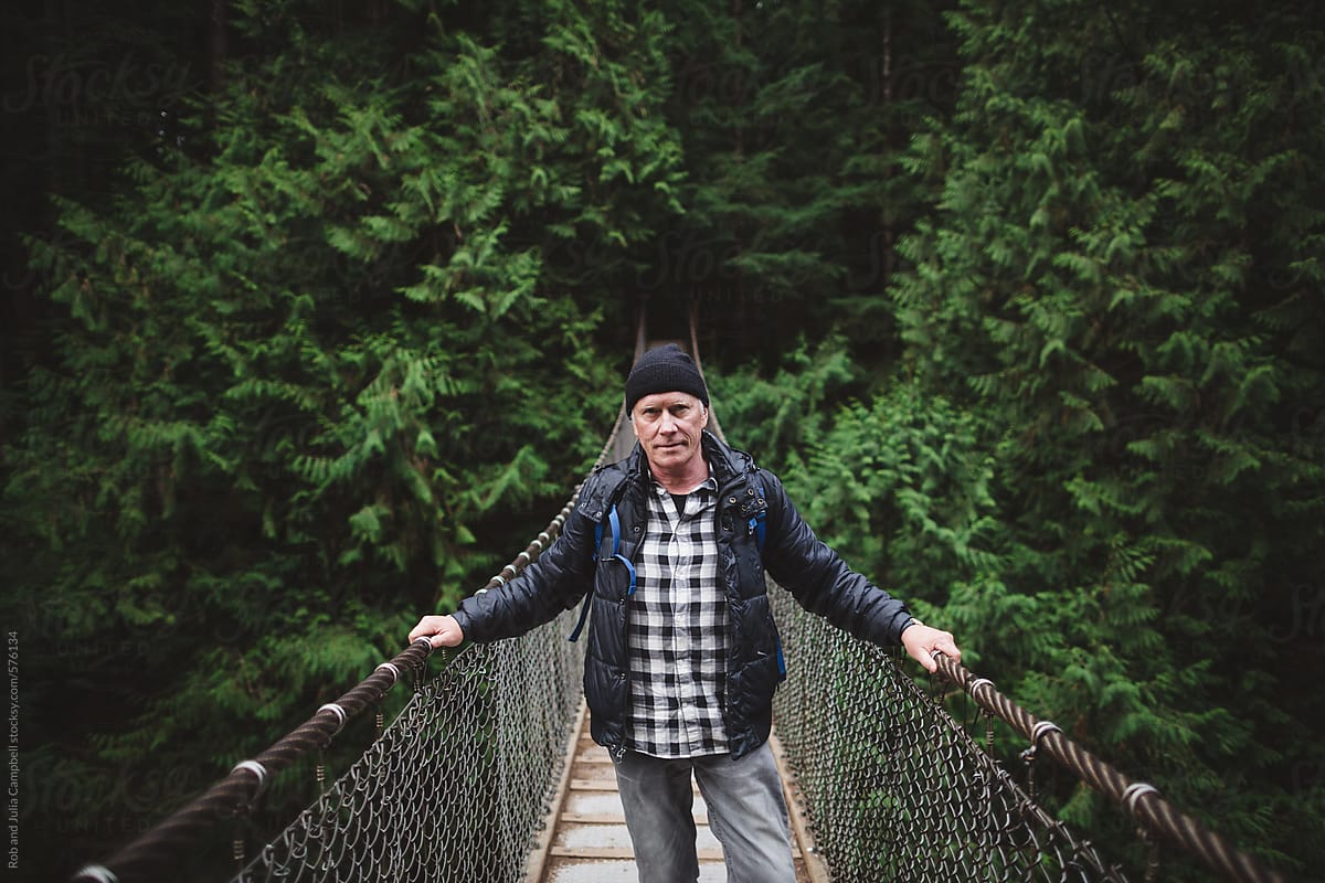 Rugged older man on a hike - portrait on a suspension bridge