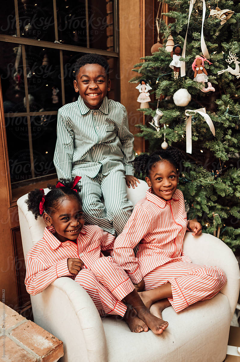 Siblings in matching pajamas during Christmas.