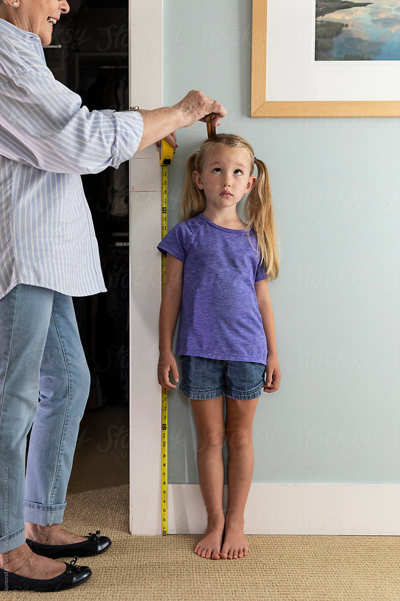 Young Girl Measuring her height against Wall