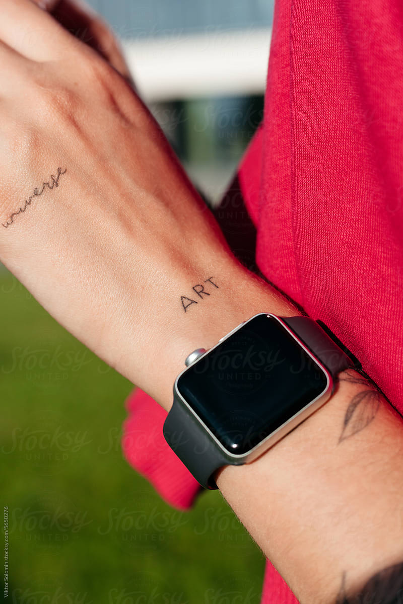 Crop woman's tanned hand with smart watch. Tattoo ART and Universe