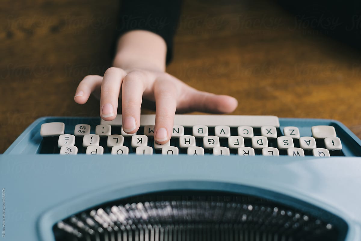 hands typing on a retro blue typewriter
