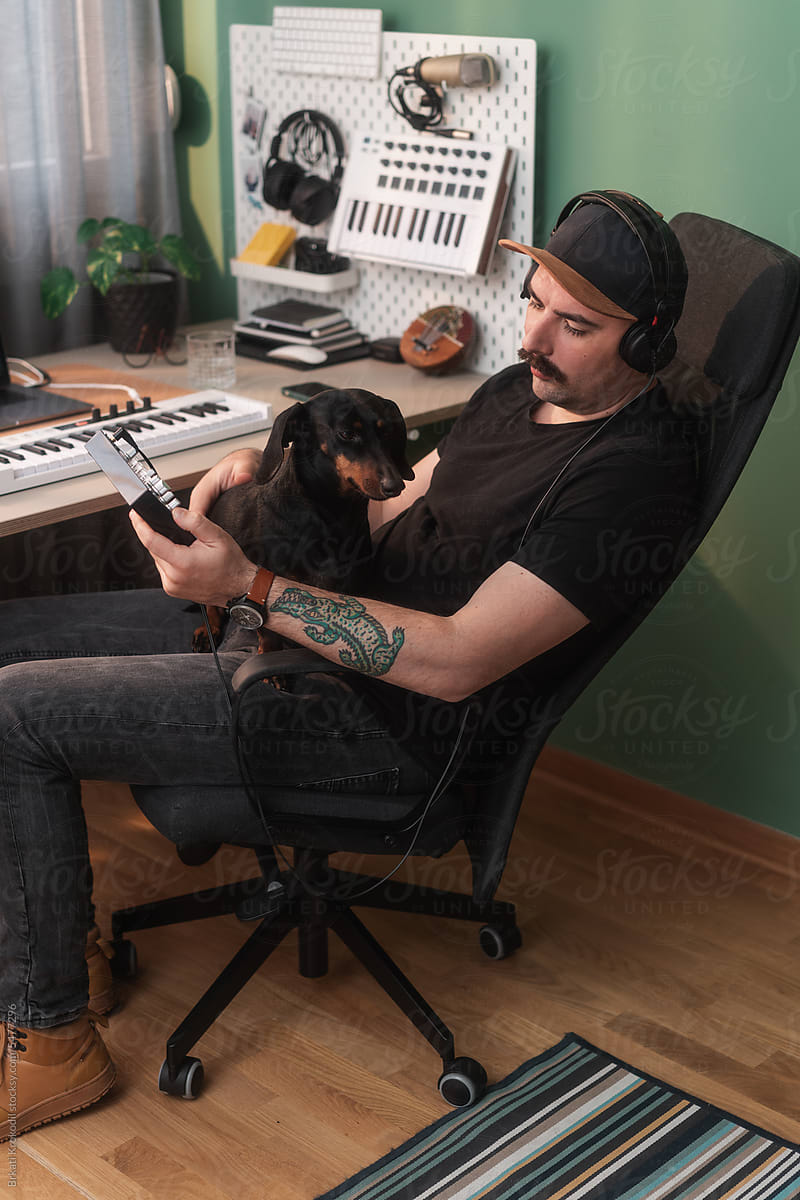 Man In His Home Workspace With A Dog Playing Music