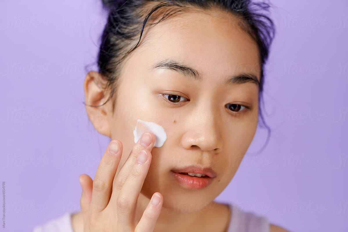 Portrait of young woman applying beauty cosmetics product on cheek